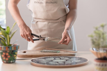 Artist cutting sheets of stained glass into small mosaic squares. Close-up