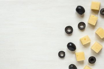 Ingredients for snacks, cheese with olives on a white table with copy space.