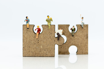 Miniature people : businessman sitting on jigsaw puzzle pieces . Image use for solve, finding solution, business vision concept.