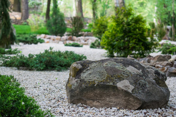 An artificial rock garden, a large and heavy stone among the many white small stones in the open-air design garden