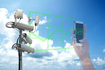 Cellular network antenna and Green rising graph chart showing on the smartphone and blue sky.