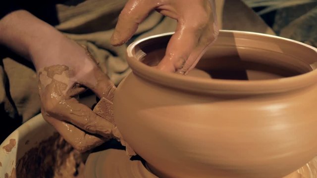A potter uses a sponge while turning a vase on a wheel. 4K.
