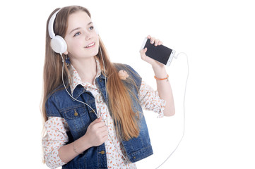 Happy little girl in jeans jacket listening music with smartphon