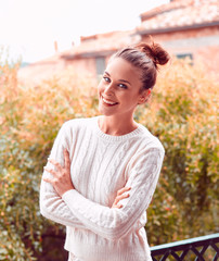Pretty laughing beautiful young woman in white sweater and underwear, standing on balcony. Tuscany, Italy. Small depth of field.