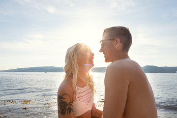 Fototapeta premium Laughing couple in love laughing at the beach against sun