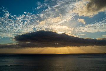 Sunset behind some clouds over the sea with orange and blue sky