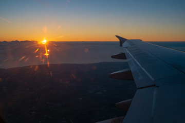 Sunset trough the window of an air plane and a wing