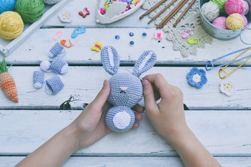 Making rabbit with carrot. Crochet bunny for child. On table threads, needles, hook, cotton yarn. Step 2 - to sew all details of toy. Handmade crafts. DIY concept. Small business. Income from hobby.