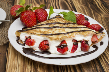 Crepes with Banana, Chocolate and strawberries on a wooden background, pancakes
