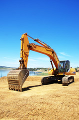 yellow excavator digging earth on nature field