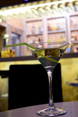 cocktail with alcohol and two olives on a stick on the bar 