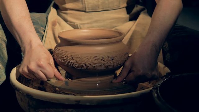Pottery worker removes a vase from a wheel, using a special line.