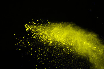 Abstract of yellow powder explosion on black background. Yellow powder splatted isolate. Colored cloud. Colored dust explode. Paint Holi.