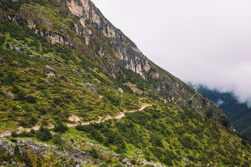 Fototapeta premium Beautiful landscape with high mountains peaks with clouds. Scenic view on the way to the Everest base camp Nepal. Mountain background. Mountain trail. Amazing scene with Himalayan mountains. Nature.