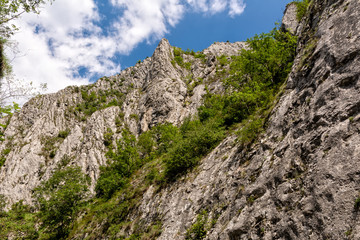 High mountain cliff edge against blue sky with clouds