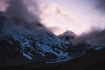 Himalayas landscape. Mountain range with trail in mist and clouds, dark sky with dim sunlight in...