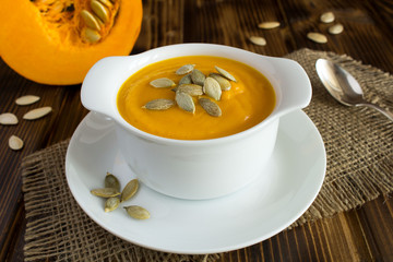 Soup with pumpkin  in the white plate on the rustic wooden  background