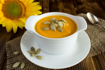 Soup with pumpkin  in the white plate on the rustic wooden  background