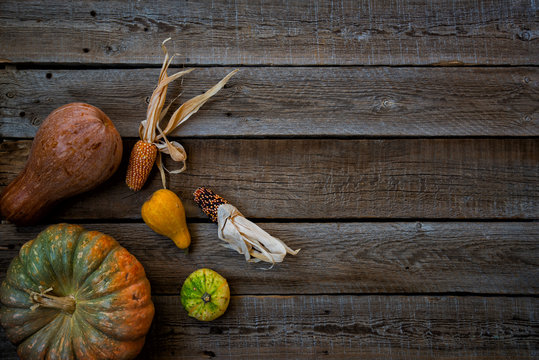 Rustic vintage background with different pumpkins and corn. Thanksgiving Day concept. Top view of varieties of pumpkins and gourds on the off vintage brown background, copy space for text. Toned image