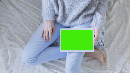 Woman relaxing reading on the tablet computer with pre-keyed green screen