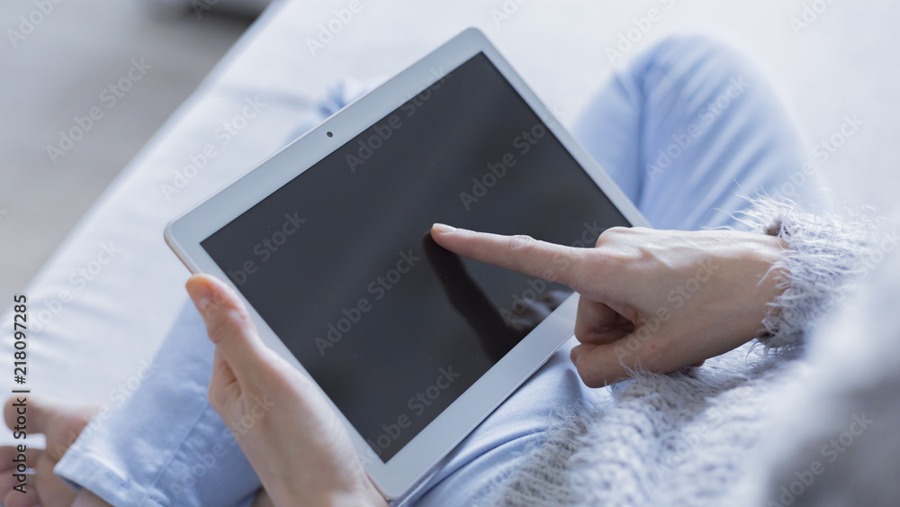 Wall mural woman is relaxing on comfortable couch and using laptop at home