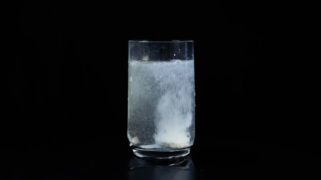 Putting Pill aspirin or vitamin In Glass With Water Splash