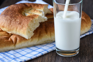 Milk is poured into a glass, bread on a kitchen towel
