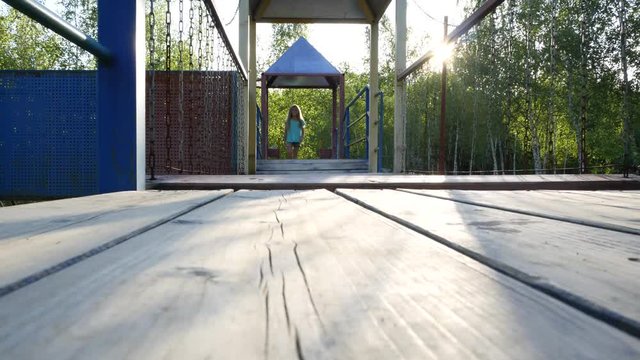 A girl on the playground walking on a straight shaky pathstraight.