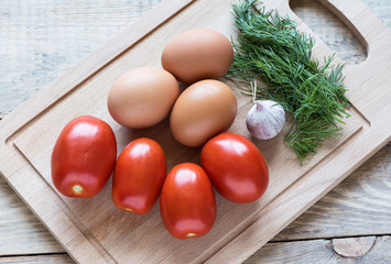 Top view. Tomatoes, eggs, garlic and dill on a cutting board