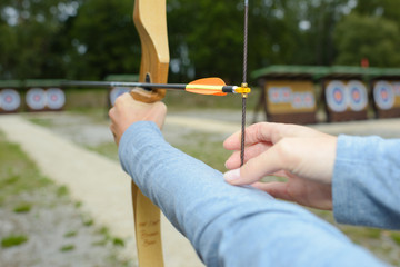 Hand poised to pull back string of bow and arrow