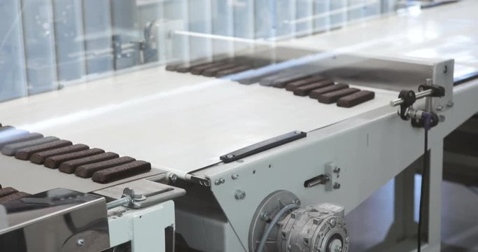 Ready chocolates on the production line at chocolate factory Manufacturing line of chocolate candy Sweet food on production line Desserts moving on conveyor belt 4K