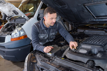 Fototapeta na wymiar mechanic unscrewing the oil tank in auto repair