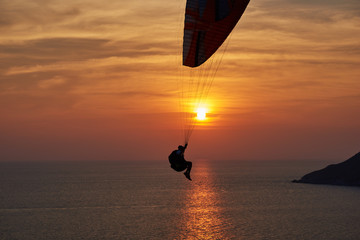 Sunset over the ocean. Silhouette of a lonely parachute on sunset background. Sky, clouds and water. Beautiful serene scene. Natural composition of nature. Landscape. Concept of outdoor activities.