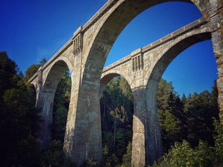 Fototapeta na wymiar Historical railway bridges made in bricks in Stańczyki, clear blue sky and green valley