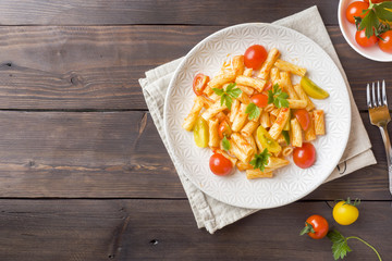 Macaroni, pasta in tomato sauce and cheese in a plate on a wooden table