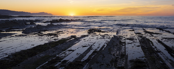 Rocky coast of Zumaia, colorfull sunset over sakoneta beach (basque country)