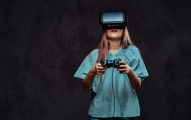 Young girl dressed casual playing the game with the joystick and virtual reality glasses. Isolated on dark textured background. © Fxquadro