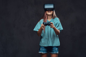 Young girl dressed casual playing the game with the joystick and virtual reality glasses. Isolated on dark textured background.