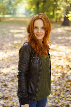 Red-haired woman standing in park on autumn day