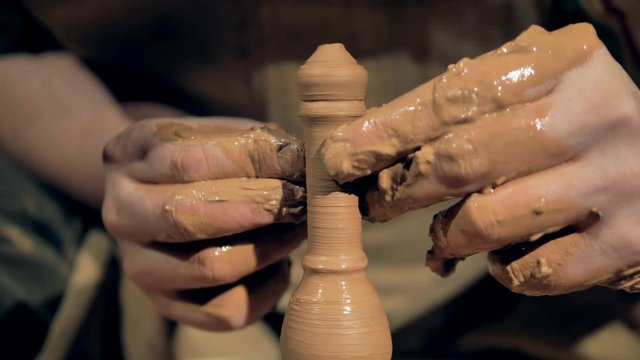 Pottery worker molds clay, shaping it with fingers into a form. 4K.