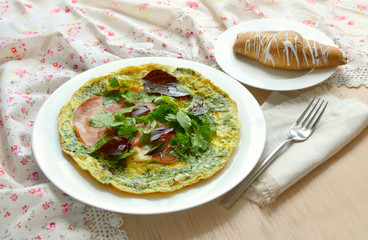 Breakfast with omelet, ham, basil and croissant.