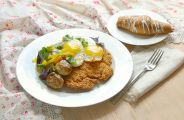 Breakfast with eggs, potatoes, schnitzel and croissant