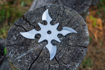 Shuriken (throwing star), traditional japanese ninja cold weapon stuck in wooden background