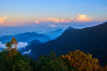 Obraz premium Mountains during sunset. Beautiful natural landscape in the summer time. A multicolored mist covered the hills. Low clouds between the peaks shrouding the most distant. Travel and adventure concept.