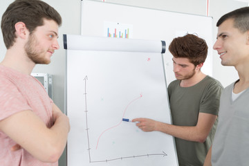 Male students looking at graph on flip chart
