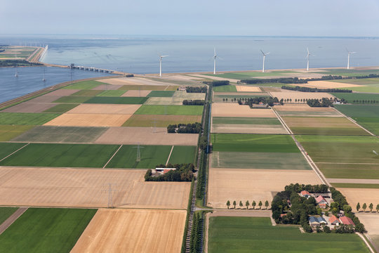 Aerial view Dutch agricultural landscape with row offshore wind turbines along the coast