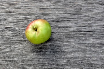 Concept of one green raw apple viewed from the top on gray wood background