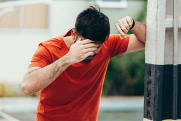 Man suffering from dizziness with difficulty standing up while leaning on wall - obrazy, fototapety, plakaty