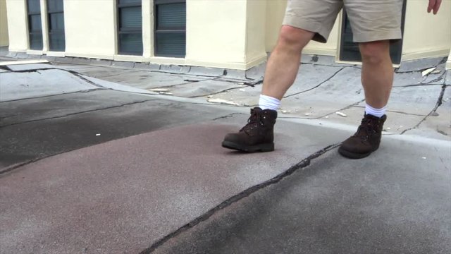 Walking over puffy areas of flat roof damaged by hurricane winds.