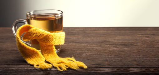Healing glass of tea in a scarf on a wooden background